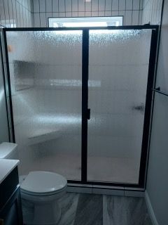 A bathroom with a toilet , shower , and mirror.