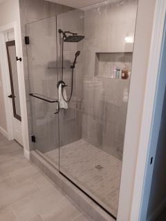 A bathroom with a walk in shower with a glass door.