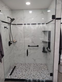 A bathroom with a walk in shower with a glass door.