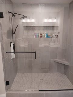 A bathroom with a walk in shower with a glass door.