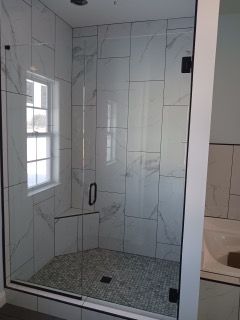 A bathroom with a walk in shower and a window.
