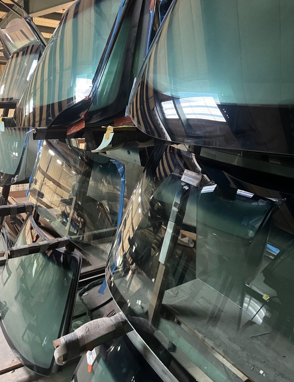 A row of windshields are stacked on top of each other in a warehouse.
