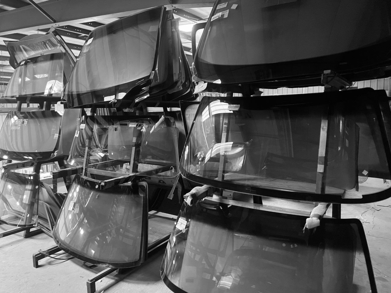 A black and white photo of a row of windshields stacked on top of each other.