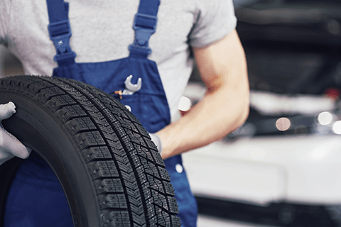 Worker Holding Black Tire — Monroe, NC — Small Bros. Tire Co Inc.