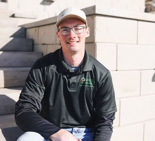 A man wearing glasses and a hat is sitting on a set of stairs