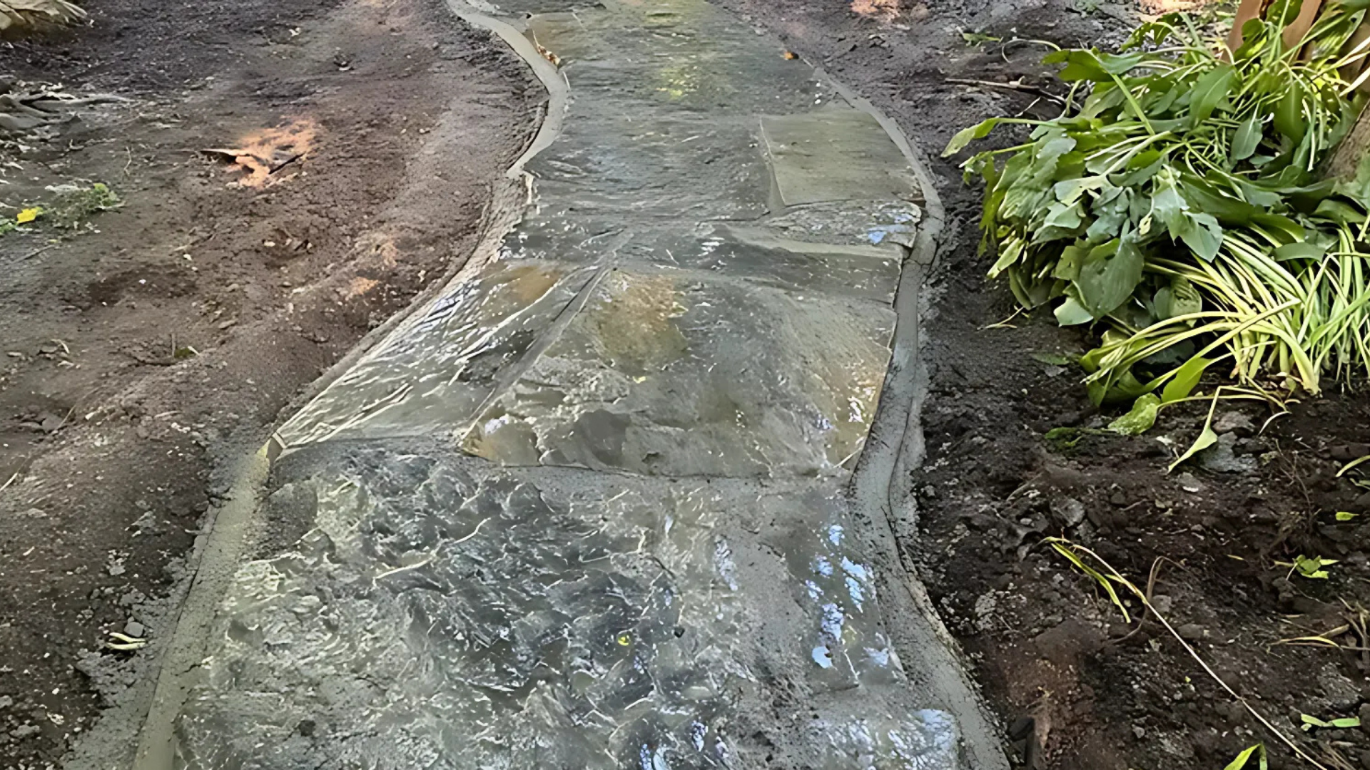 A stone walkway is being built in the dirt in a garden.