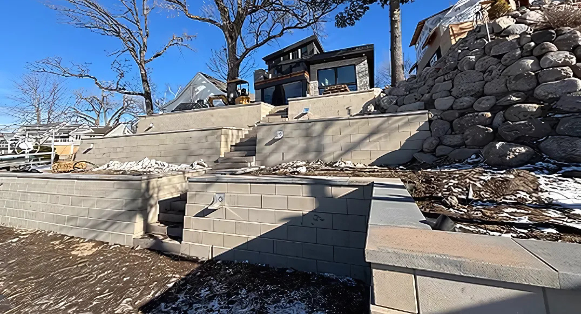 A house is sitting on top of a hill next to a stone wall.