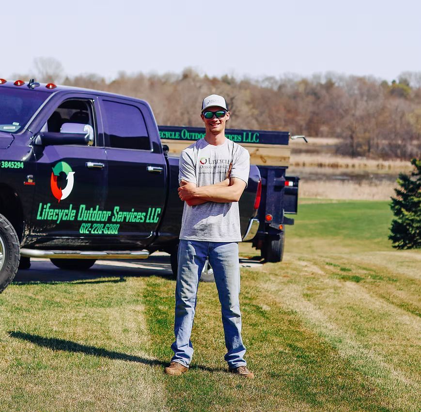 A man stands in front of a lifecycle outdoor services truck