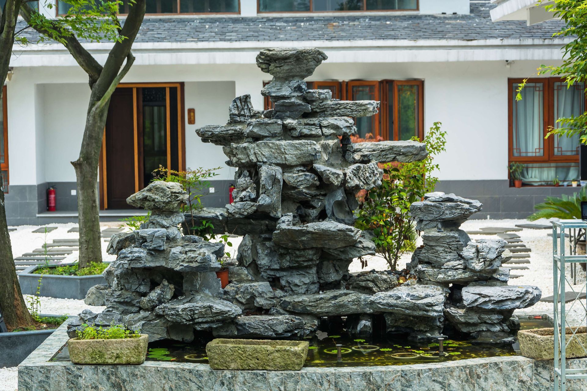 A large stone fountain is in front of a house.