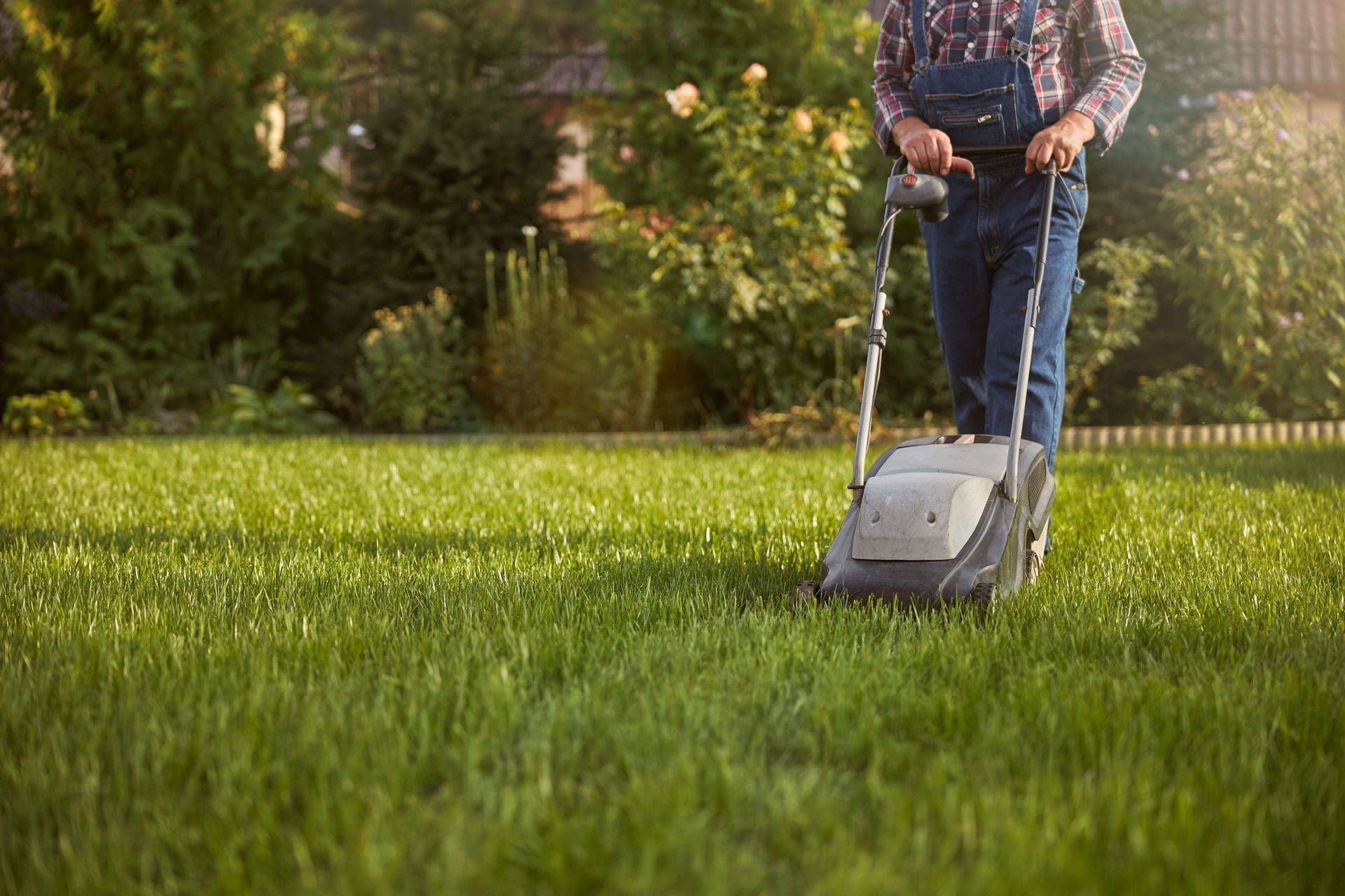 A man is mowing his lawn with a lawn mower.