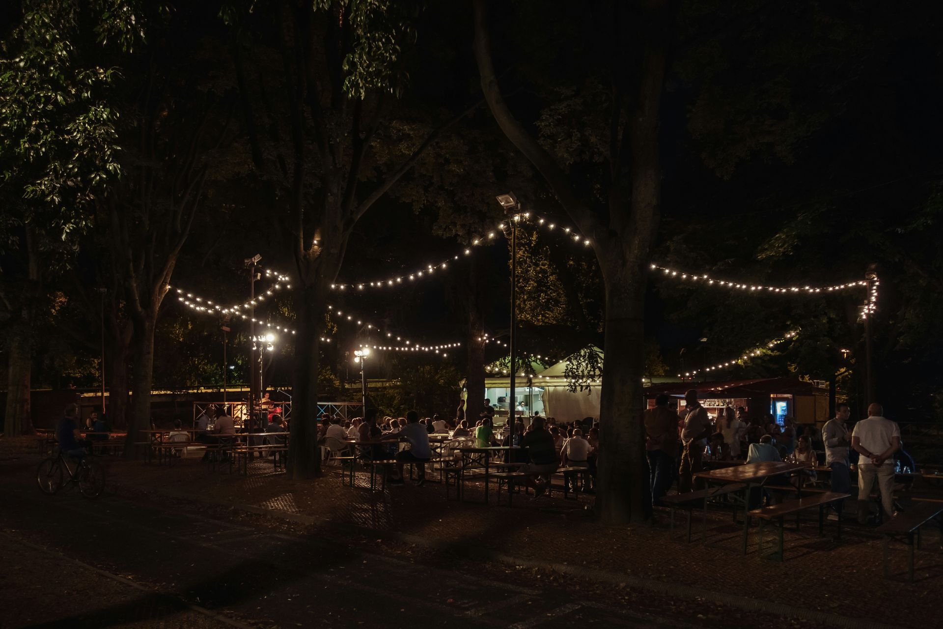 A group of people are sitting at tables in a park at night.