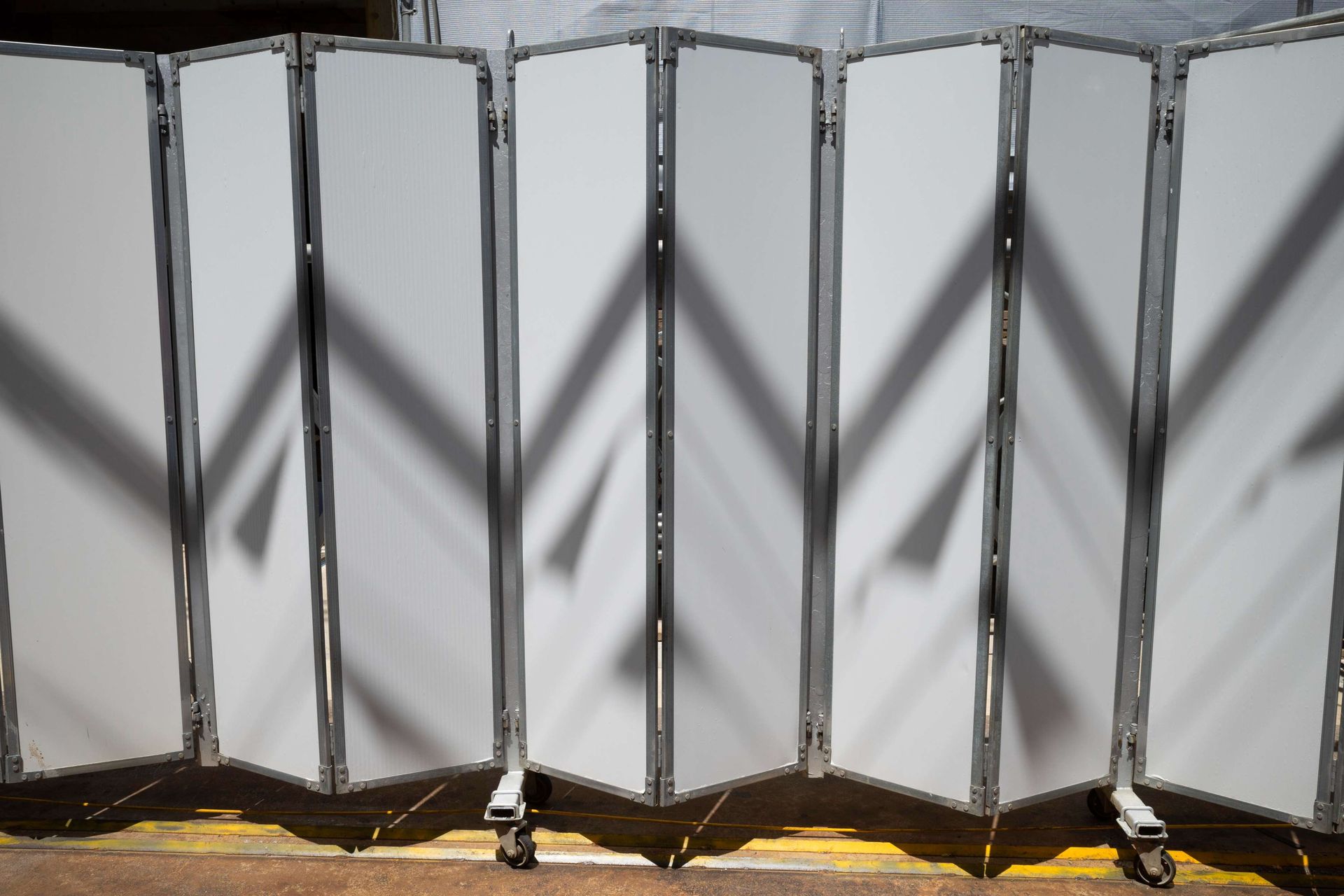A row of white folding screens with shadows on them