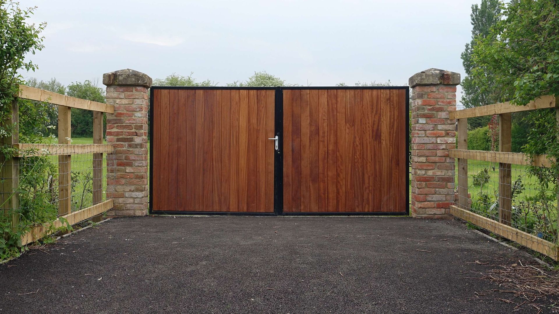 A wooden gate is surrounded by a brick wall and a wooden fence.