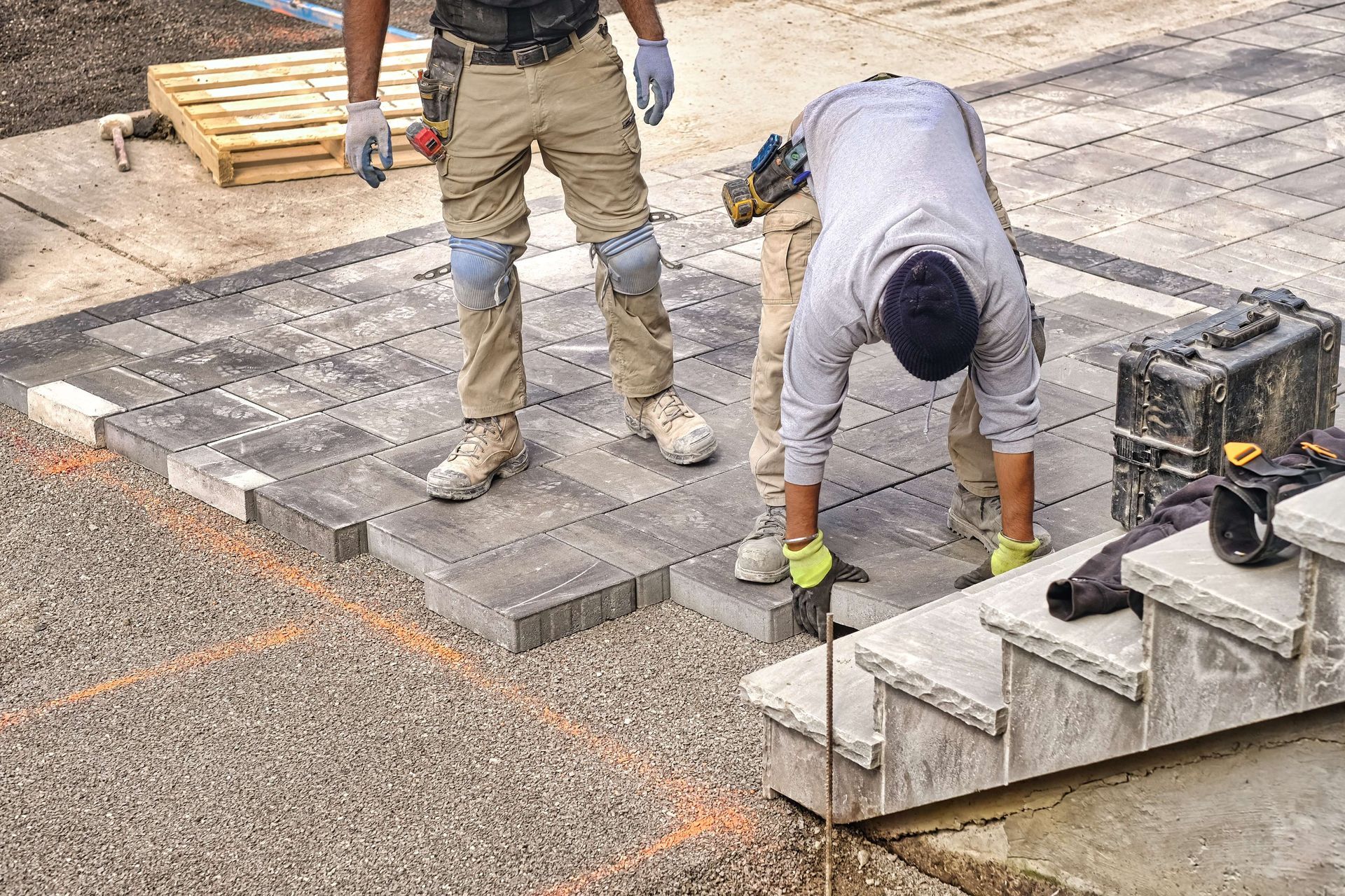 Two men are working on a patio and stairs.