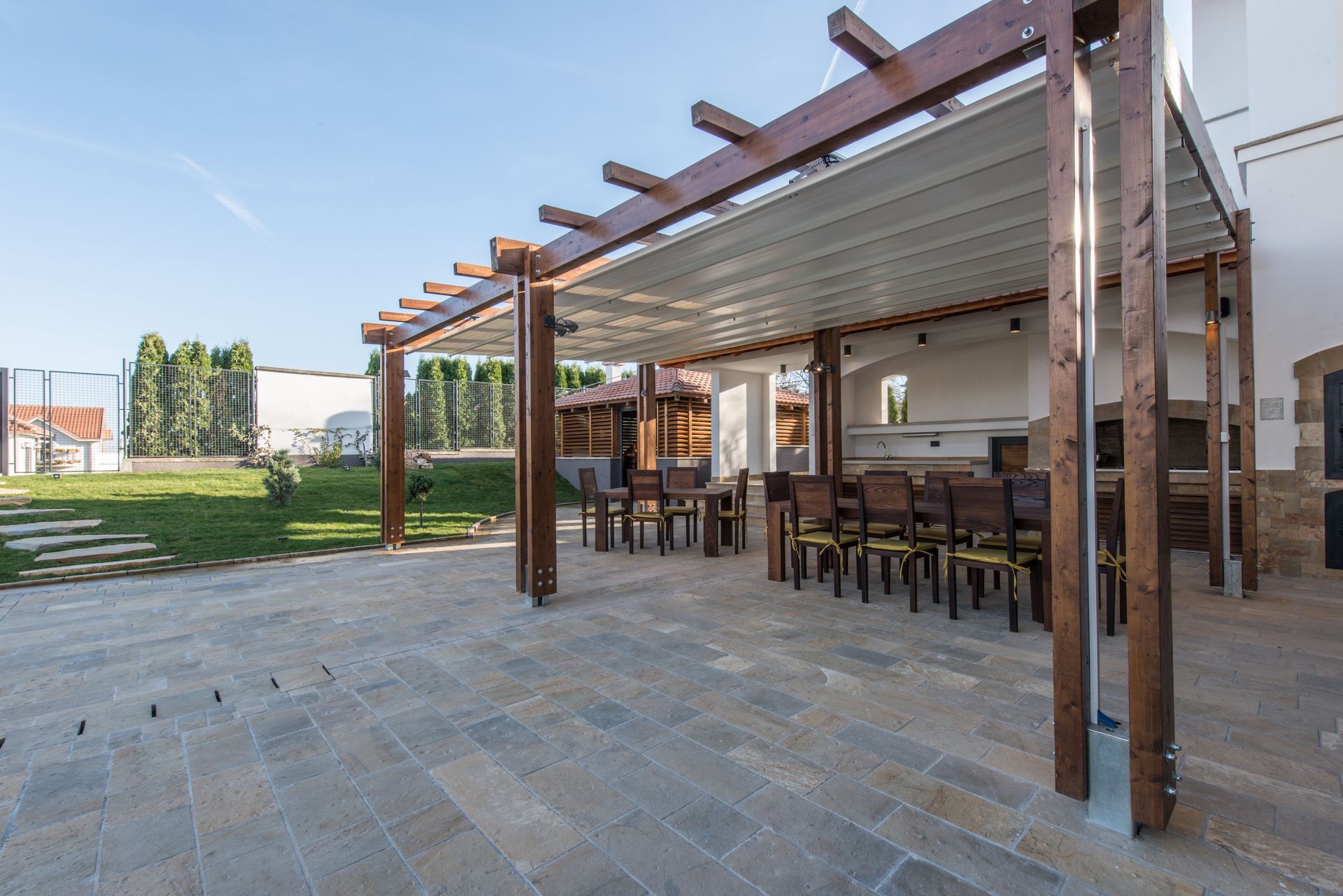 A wooden pergola with a table and chairs underneath it.