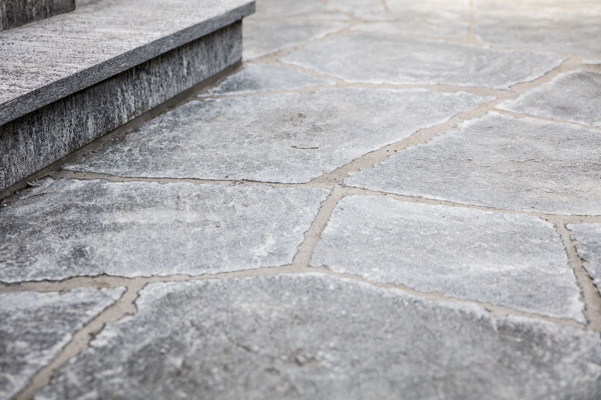 A close up of a stone floor with stairs in the background.