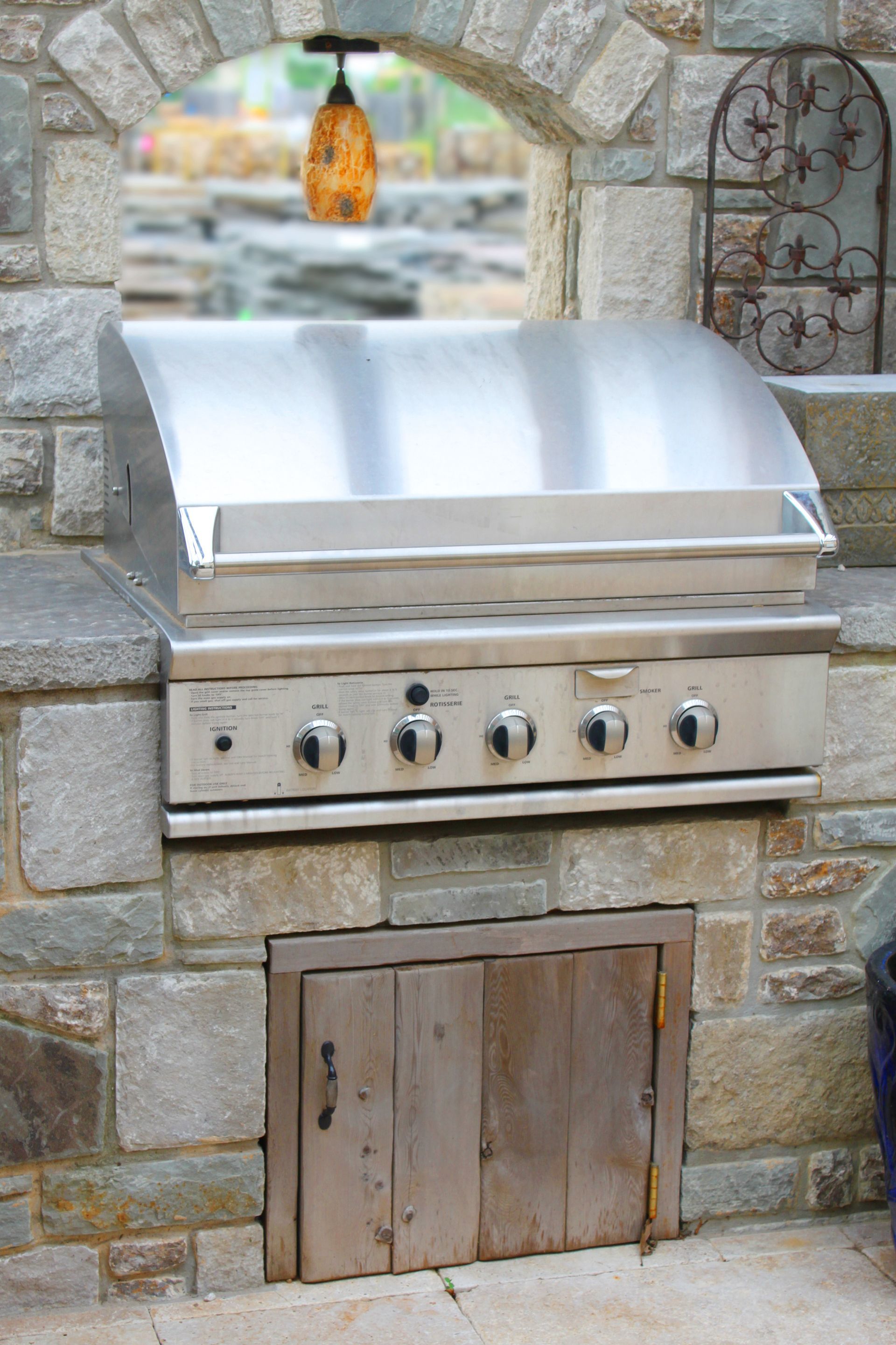 A stainless steel grill is built into a stone wall.