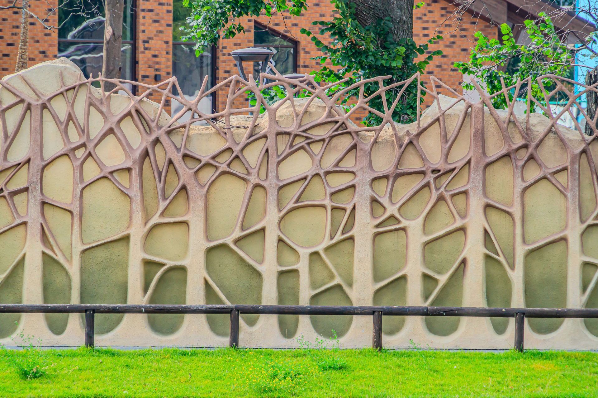 A fence with trees carved into it and a wooden fence in front of a brick building.