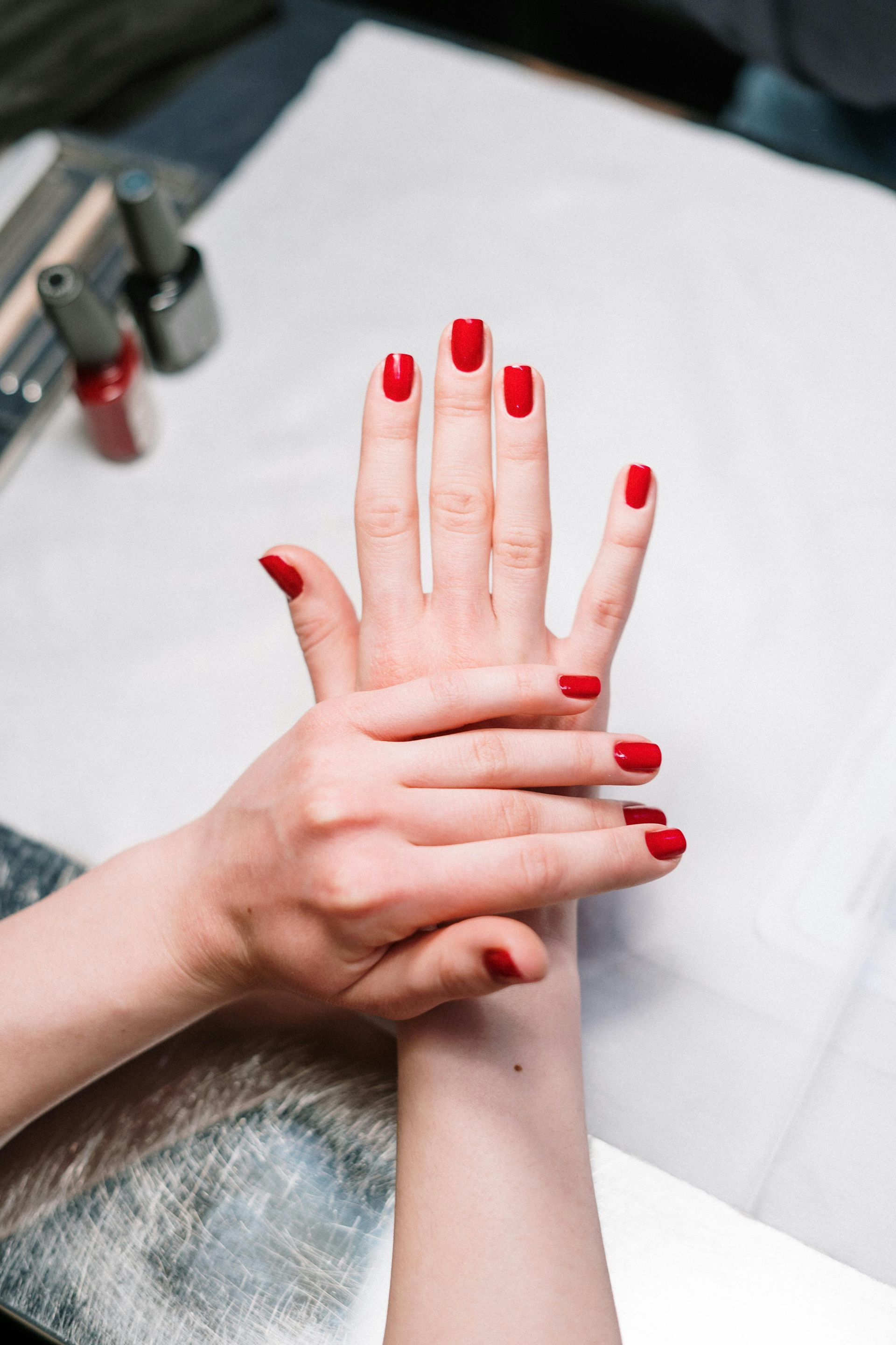 Une femme aux ongles rouges se fait faire une manucure dans un salon de manucure.