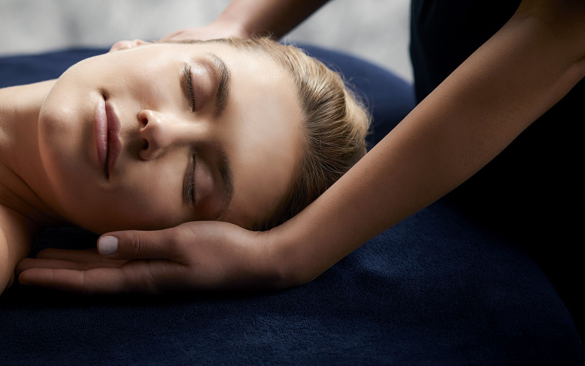Une femme se fait masser dans un spa les yeux fermés.