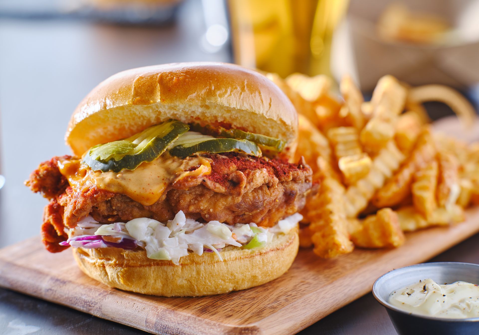 Fried chicken sandwich with fries on a wooden board.