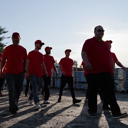 Group of people in red shirts and hats walking towards the camera outdoors.