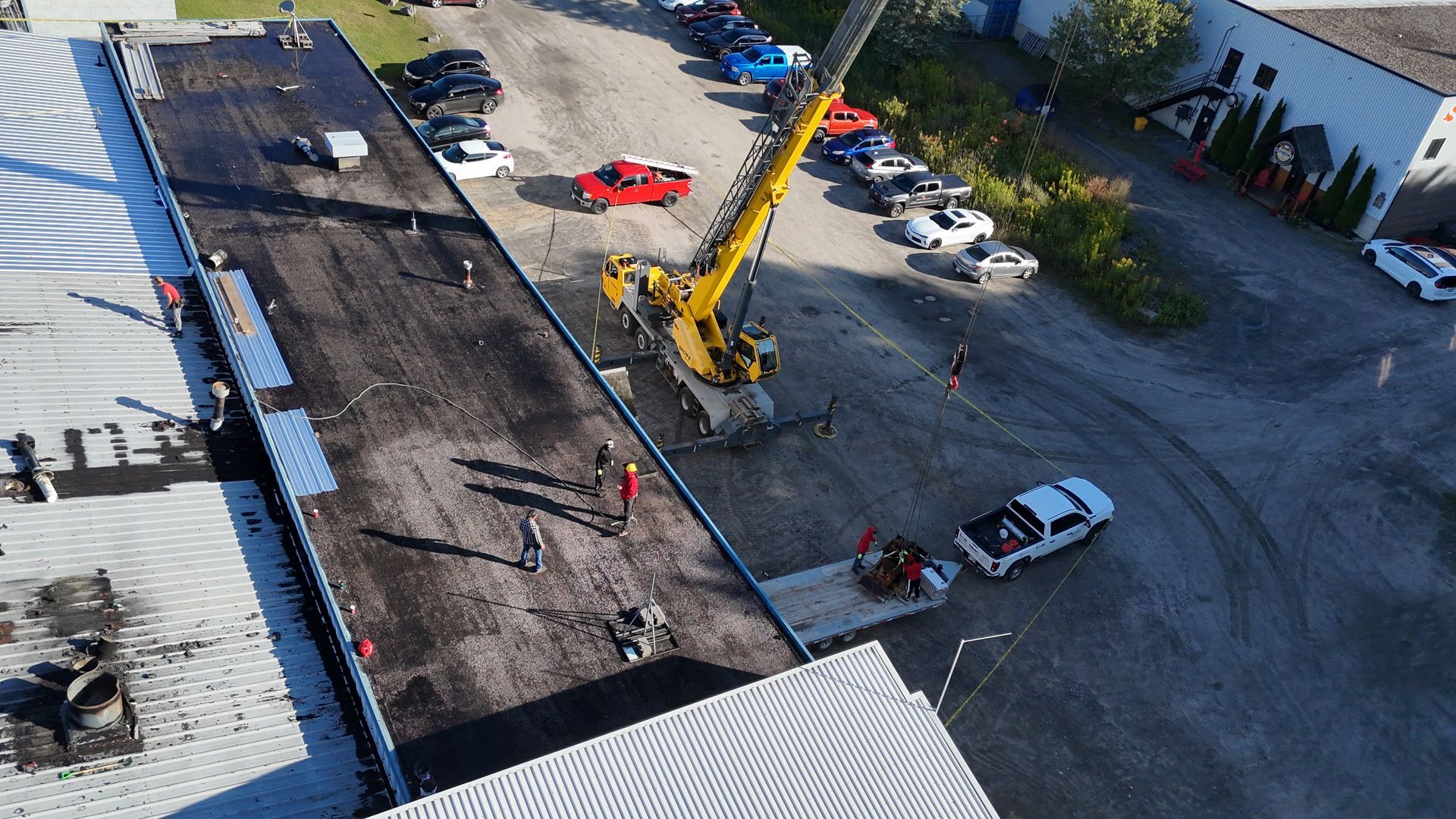 Asphalt paving in progress; crane, workers, and vehicles on site.