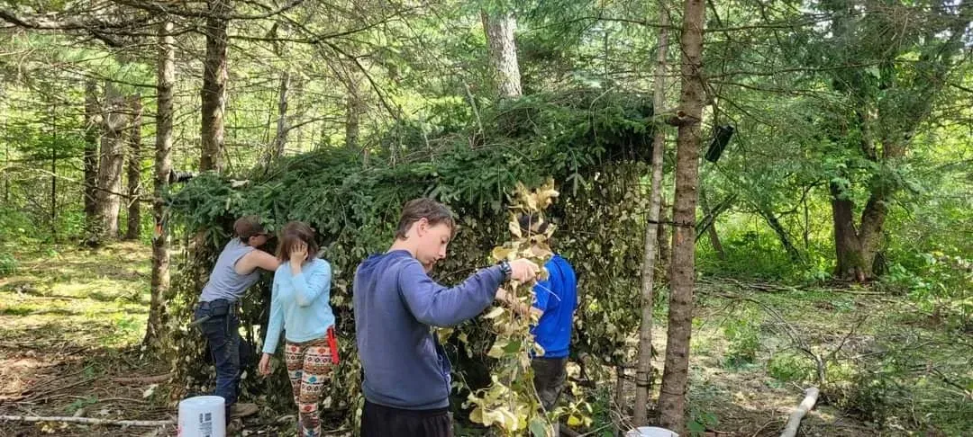 A group of people are building a shelter in the woods.