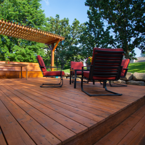 A wooden deck with chairs and a table under a pergola
