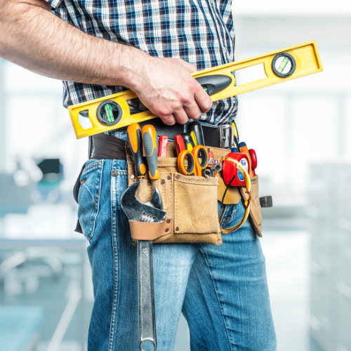 A man wearing a tool belt is holding a yellow level.
