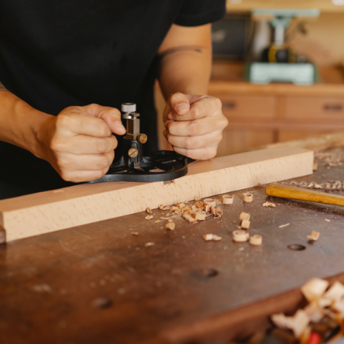 A man is using a plane to plane a piece of wood.