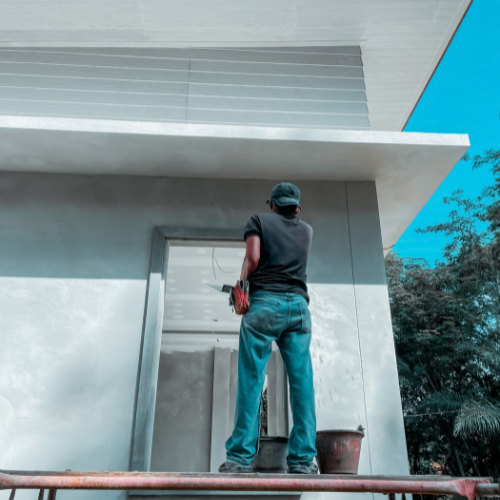 A man is standing on a scaffolding in front of a building