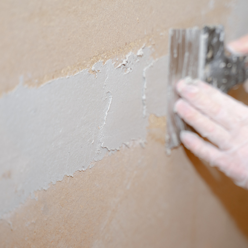 A person is plastering a wall with a spatula.