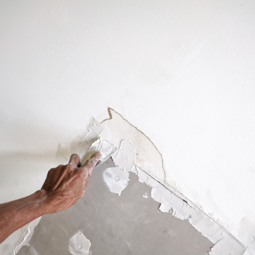 A person is plastering a wall with a spatula.