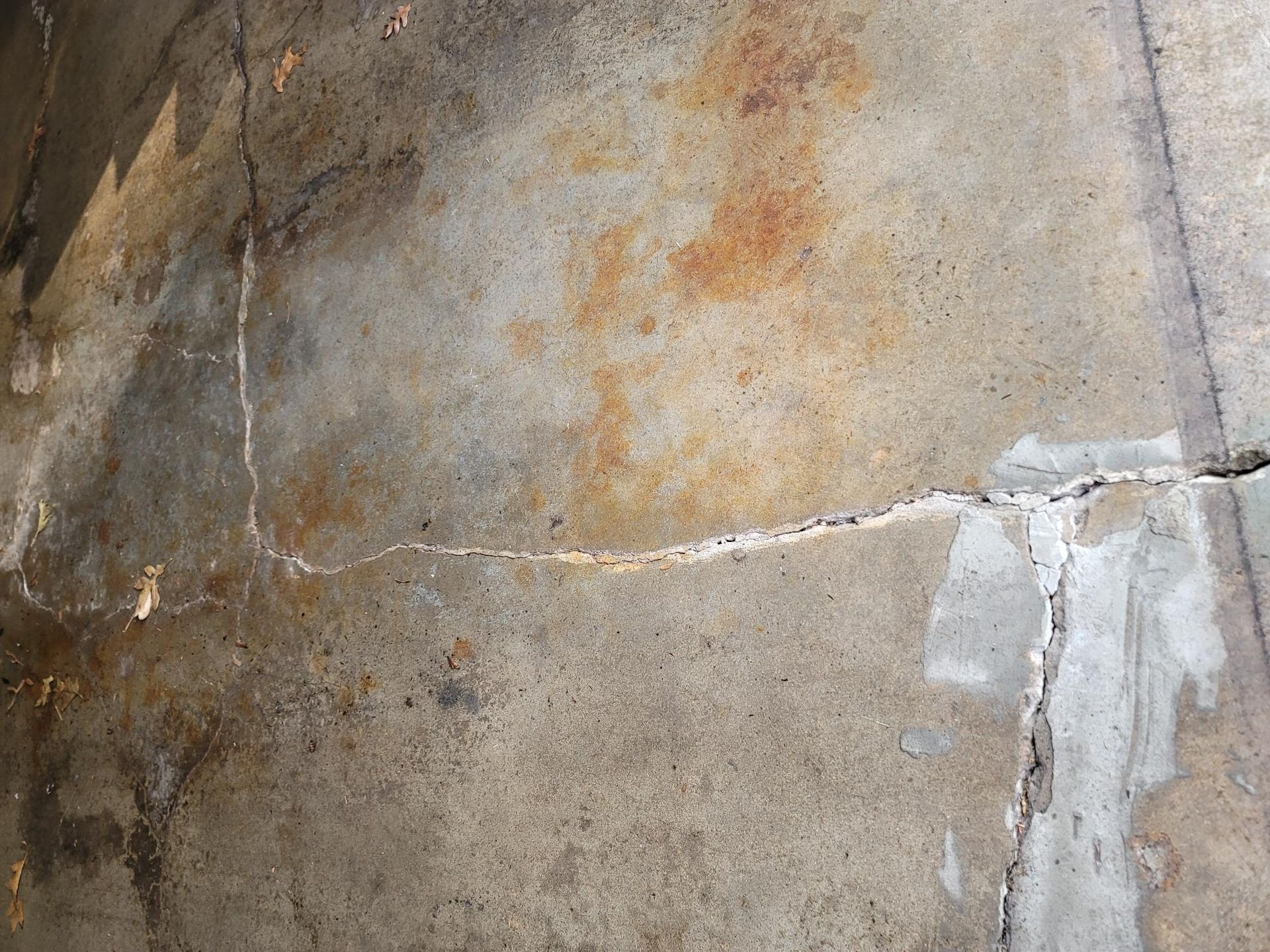 Cracked, stained concrete surface, with areas of white patching visible.