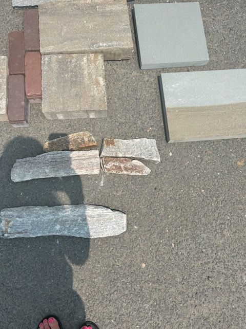 Various paving stones in gray, brown, and red on asphalt.