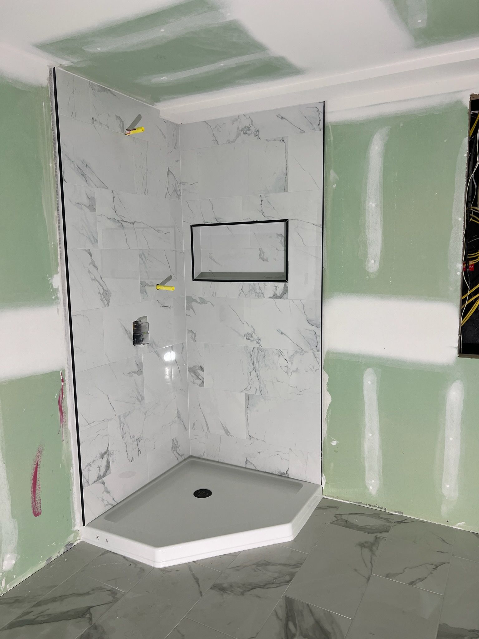 Newly tiled shower with gray marble-look walls, corner entry, and built-in niche.