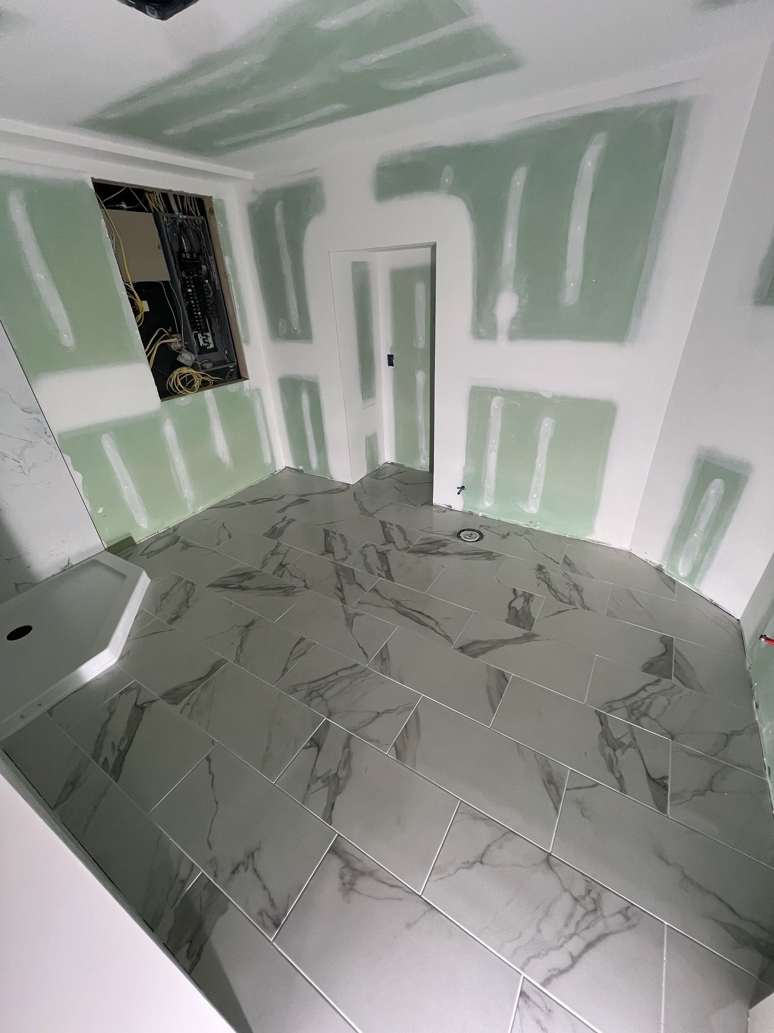 Bathroom under construction with marble tile floor and drywall walls.