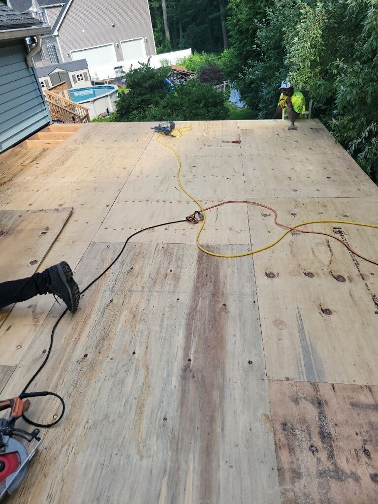 A person is cutting a piece of plywood on a roof.