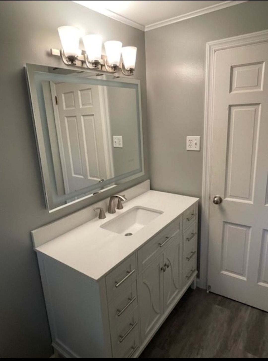 A bathroom with a sink , mirror and light fixture.