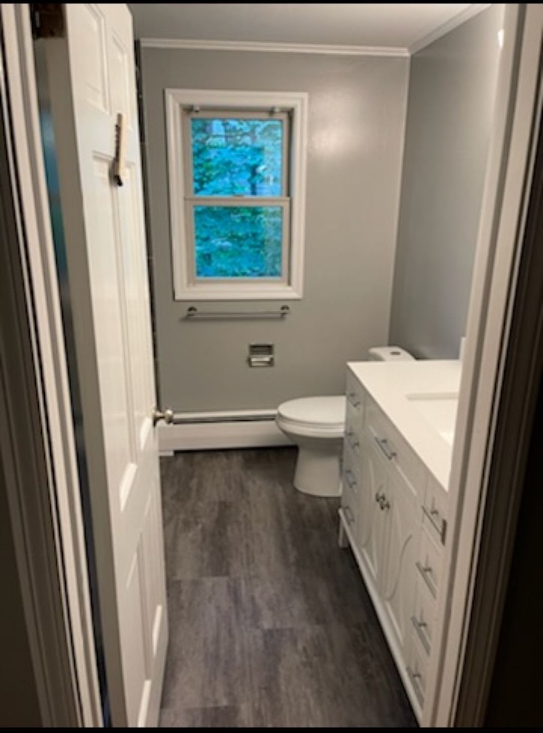A bathroom with a toilet , sink and window