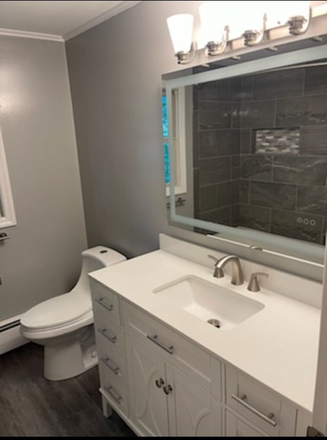 A bathroom with a toilet , sink and mirror