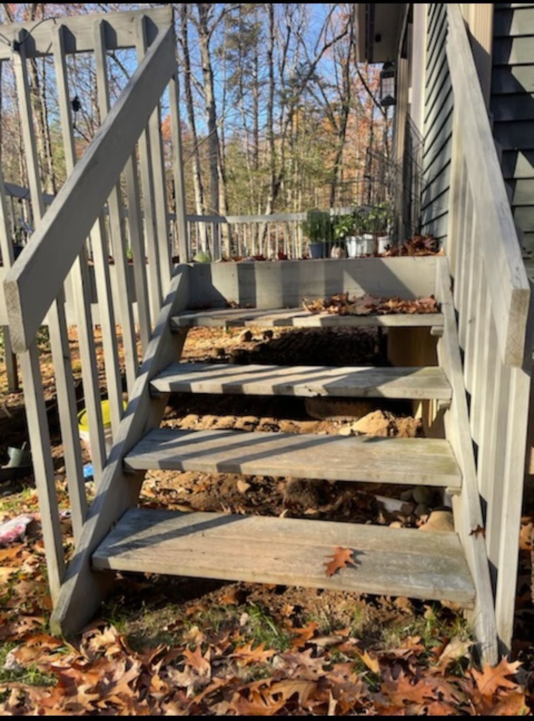 A set of wooden stairs leading up to a house with leaves on the ground