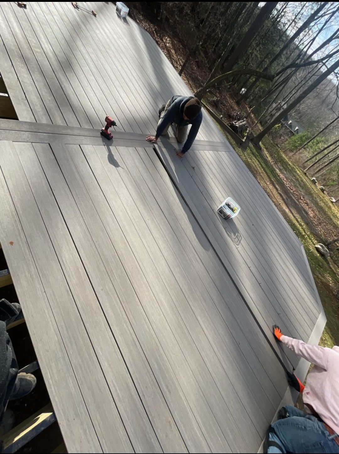 A man is working on a wooden deck in the woods.