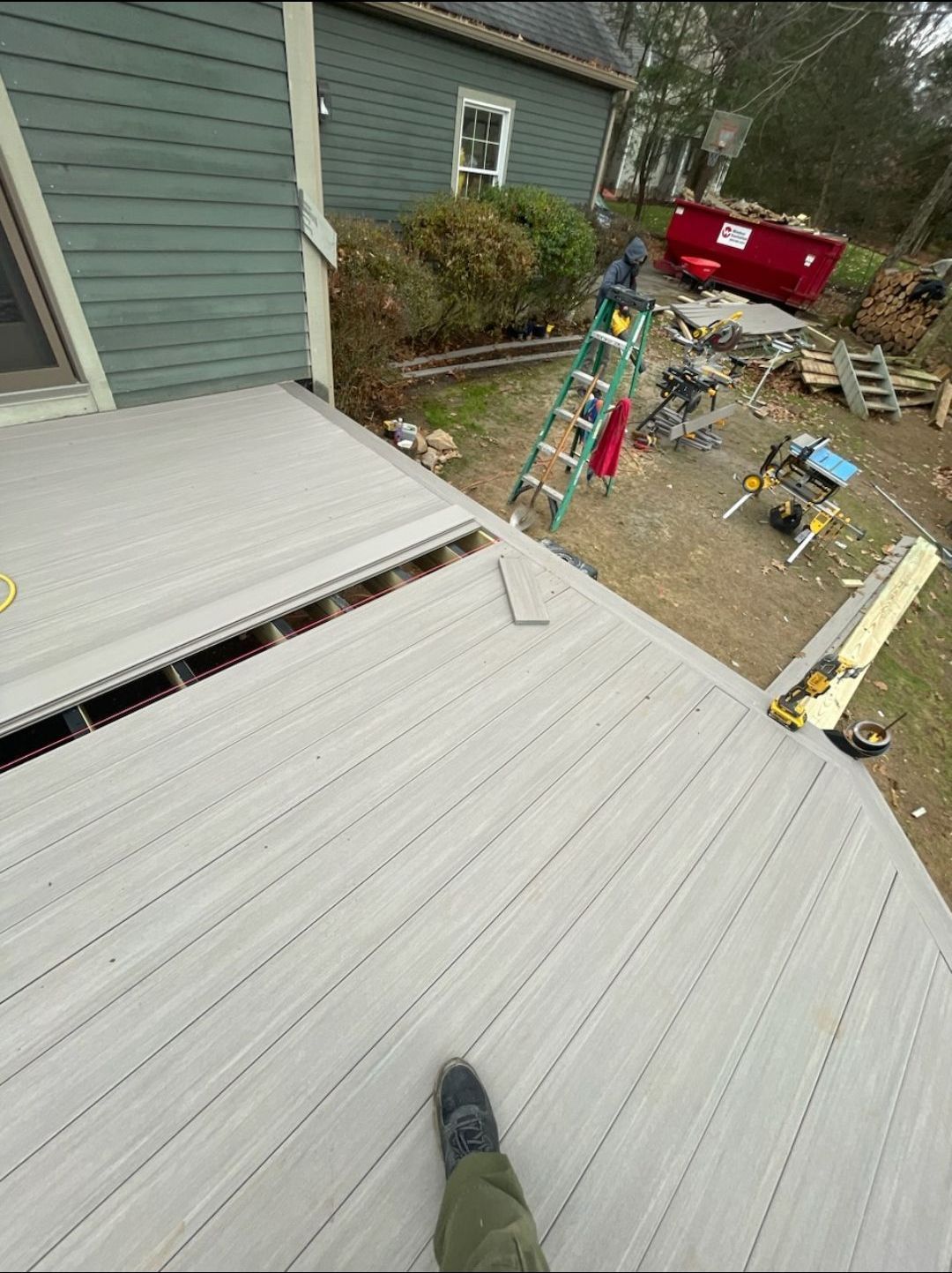 A person is standing on a deck in front of a house.