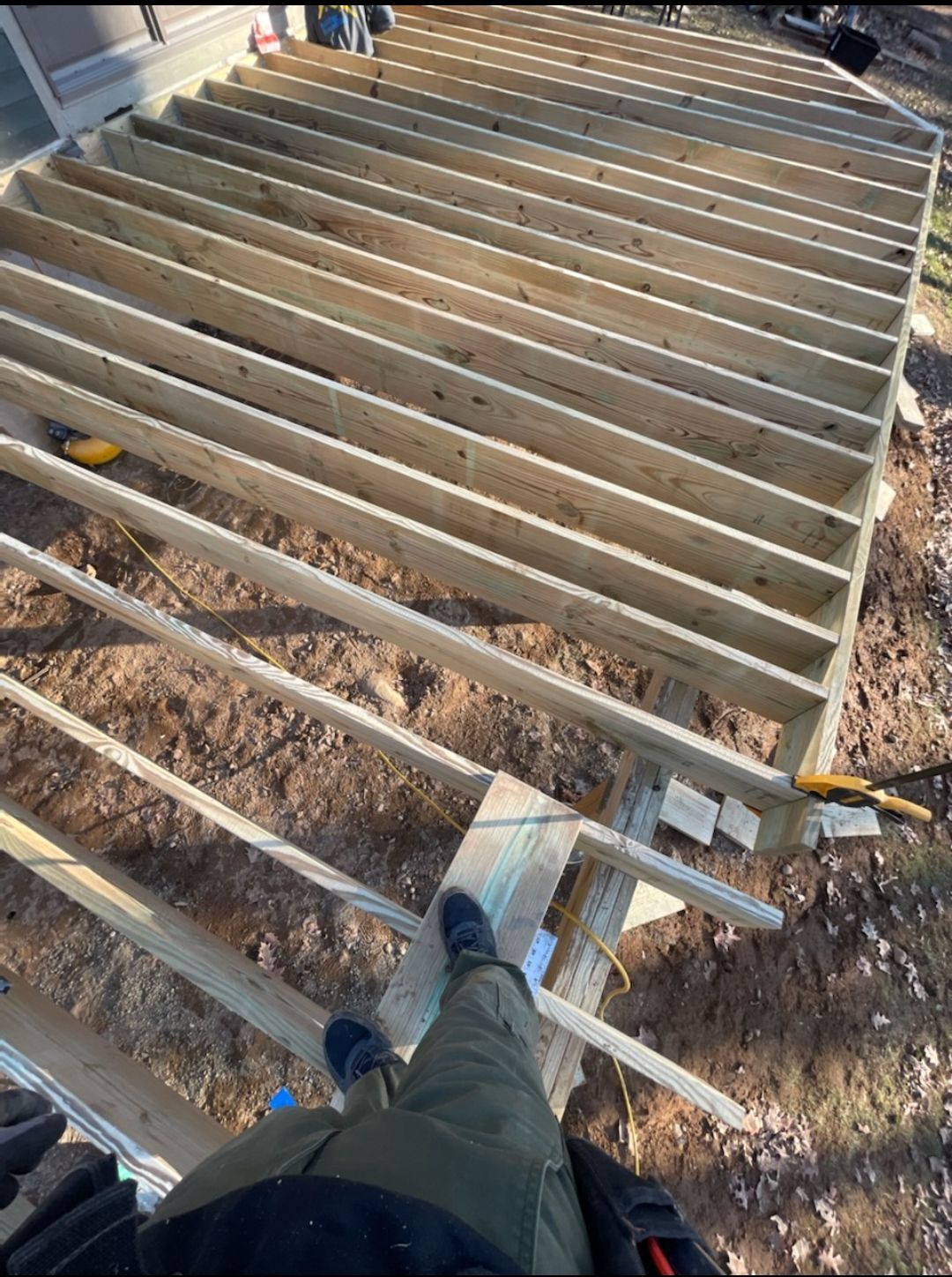 A person is standing on top of a wooden deck under construction.