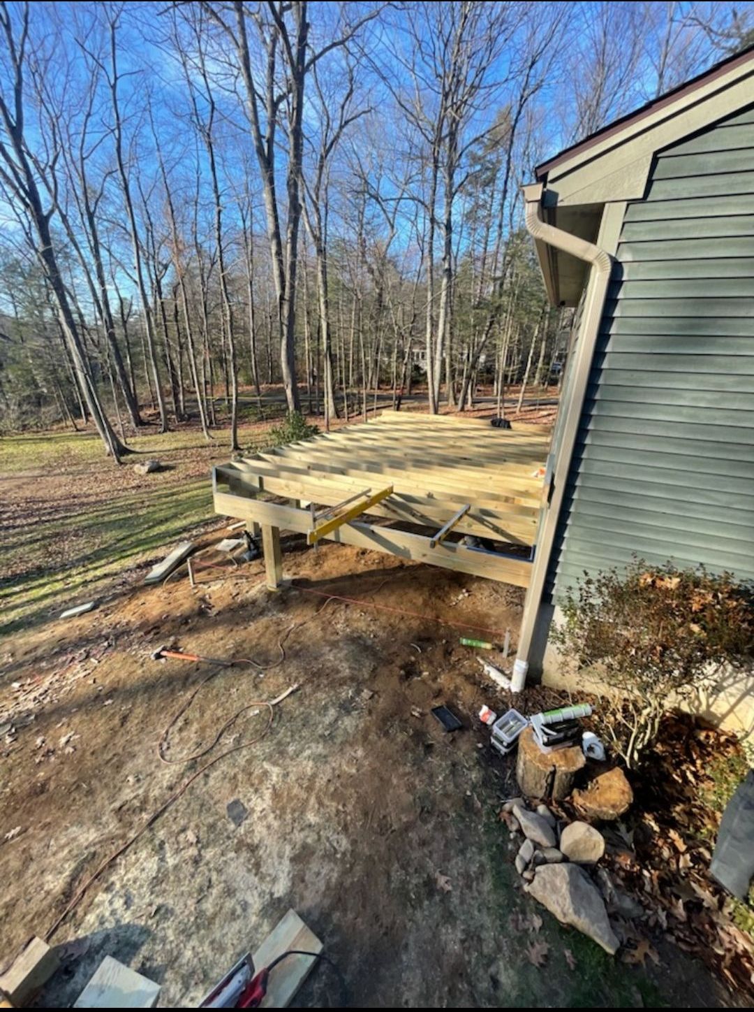 A wooden deck is being built on the side of a house.