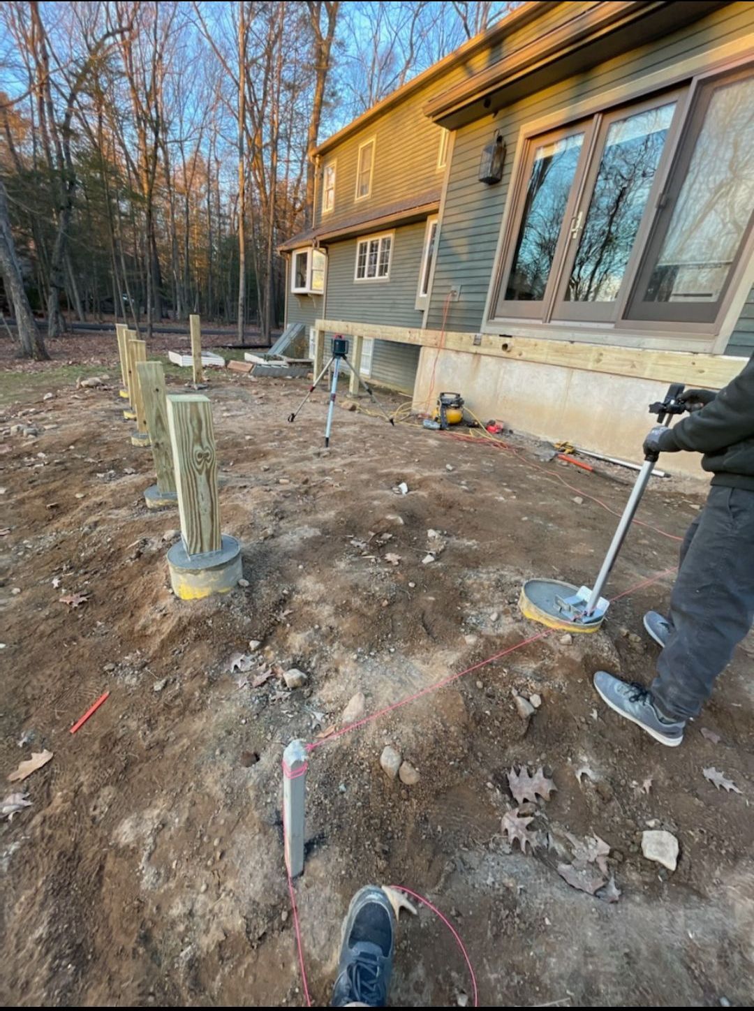 A man is using a metal detector in front of a house.