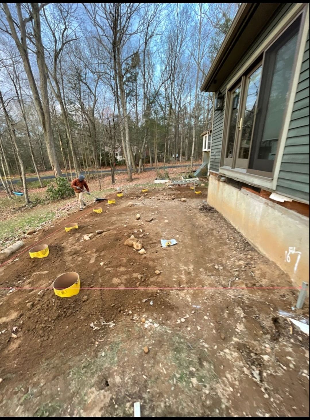 A man is standing in the dirt in front of a house.