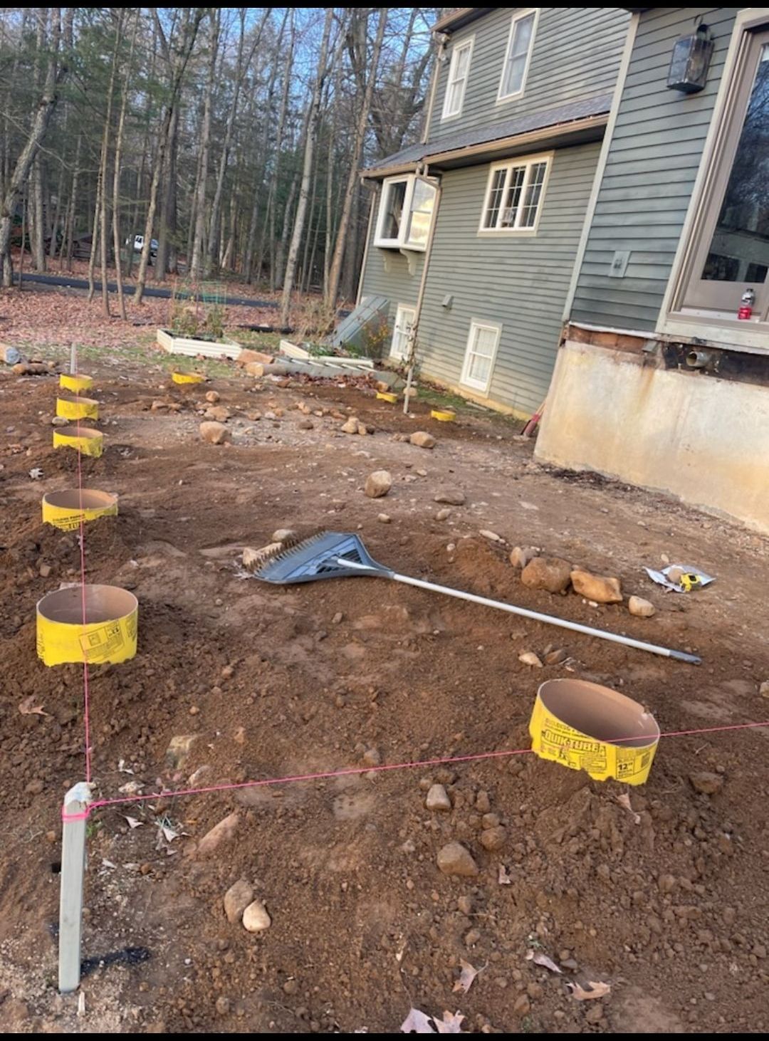 A shovel is sitting in the dirt in front of a house.